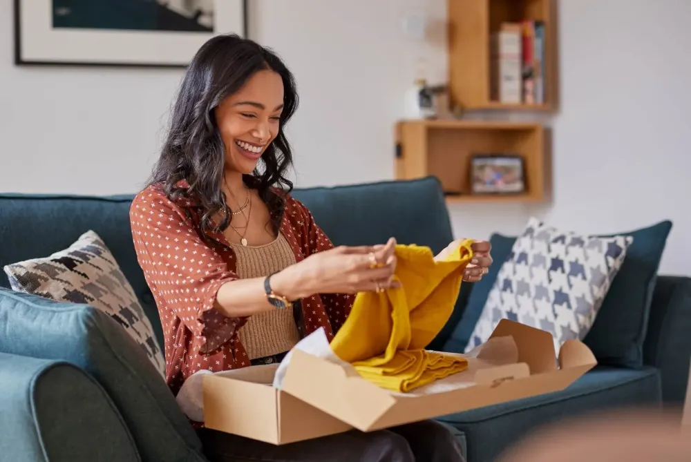 Woman unboxing an e-commerce parcel, showcasing a premium and personalised customer experience at delivery