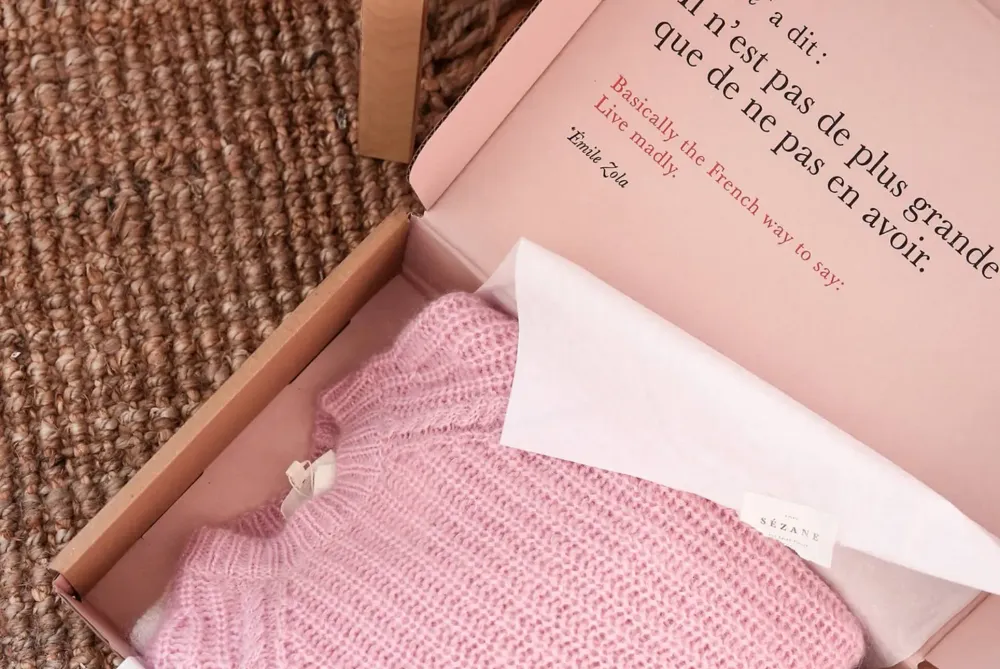 Sézane unboxing experience with a subtle scent, delicate tissue paper, and an elegant message card — designed to engage all the senses.
