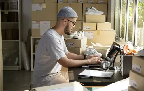 E-commerce shipping boxes and parcels on a warehouse table, illustrating strategies to reduce shipping costs for small, medium and large volumes.